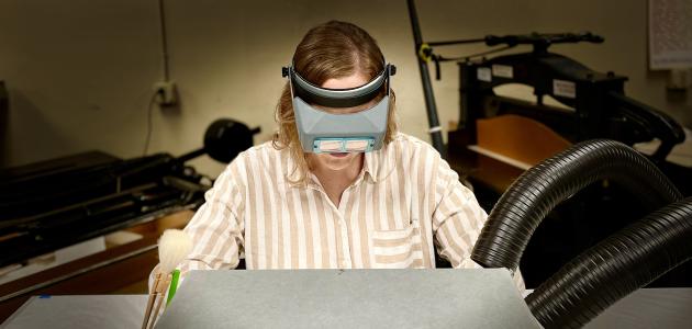 Photograph of person doing conservation work partially hidden by an archival box