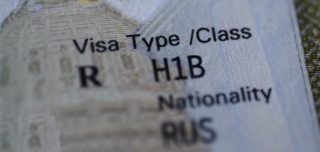 Fragment of H1B visa (for specialty workers) stamp in passport, blurred april calendar on background. H1B visa program deadline concept. Close up view. stock photo