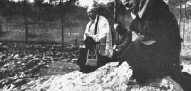 Father Stanislaw Jasinski, representative of the bishop of Krakow, prays over the mass graves