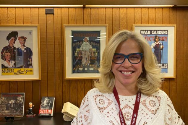 Roxanne Peck standing in front of a wall of posters and books on a table