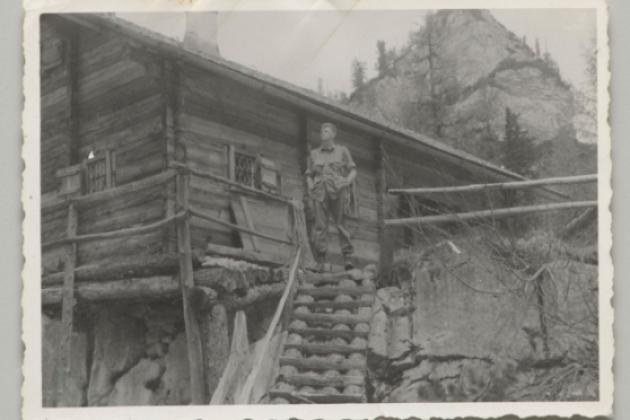 US soldier Donald Wayne Richardson standing in front of a log cabin.