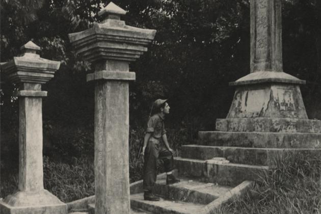 Black and white photograph of a US Navy Seabee exploring a monument on Okinawa durring WWII