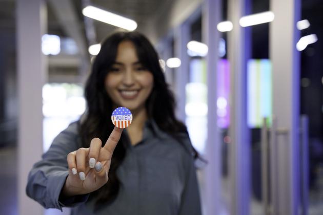 Young Hispanic Woman in Her Twenties Proudly Displaying Her I Voted Sticker in a Co-Working Space stock photo