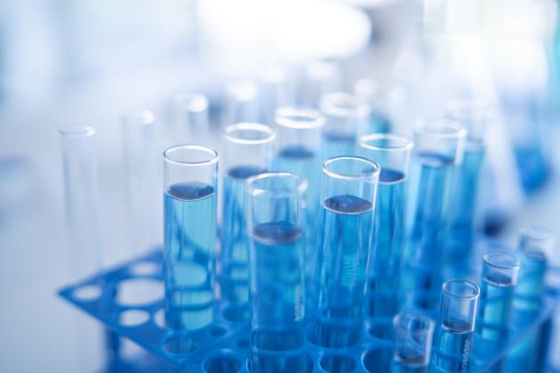 Science laboratory test tubes row with light blue liquid close-up - stock photo