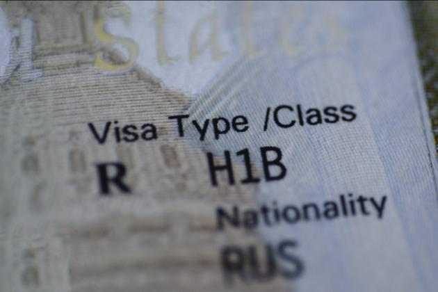 Fragment of H1B visa (for specialty workers) stamp in passport, blurred april calendar on background. H1B visa program deadline concept. Close up view. stock photo