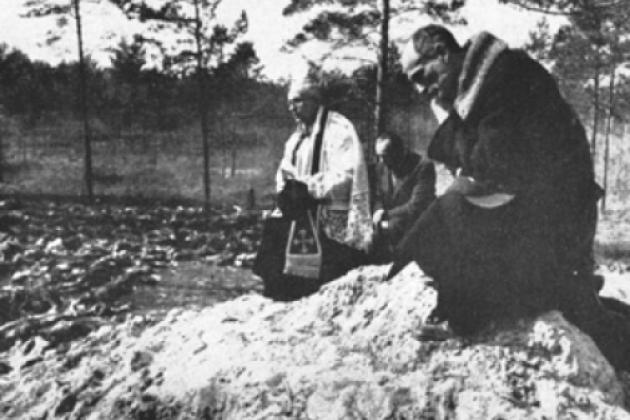 Father Stanislaw Jasinski, representative of the bishop of Krakow, prays over the mass graves