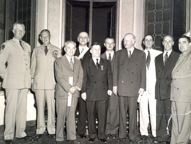 Group of men standing for a photo. Nicholas Feodoroff (front row center) with Herbert Hoover (front row right).