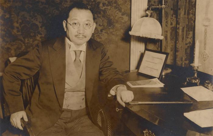 Sepia tone photograph of H. H. Kung seated at desk, 1930s