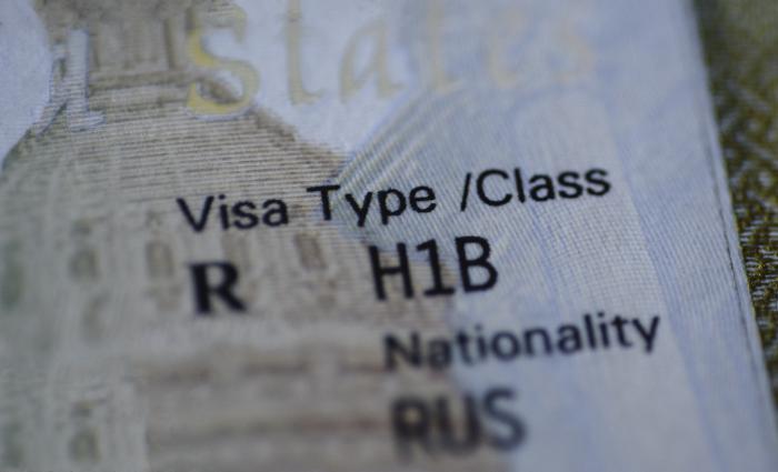 Fragment of H1B visa (for specialty workers) stamp in passport, blurred april calendar on background. H1B visa program deadline concept. Close up view. stock photo