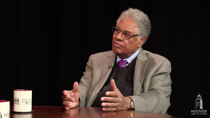 Thomas Sowell in front of a black background with an Uncommon Knowledge mug