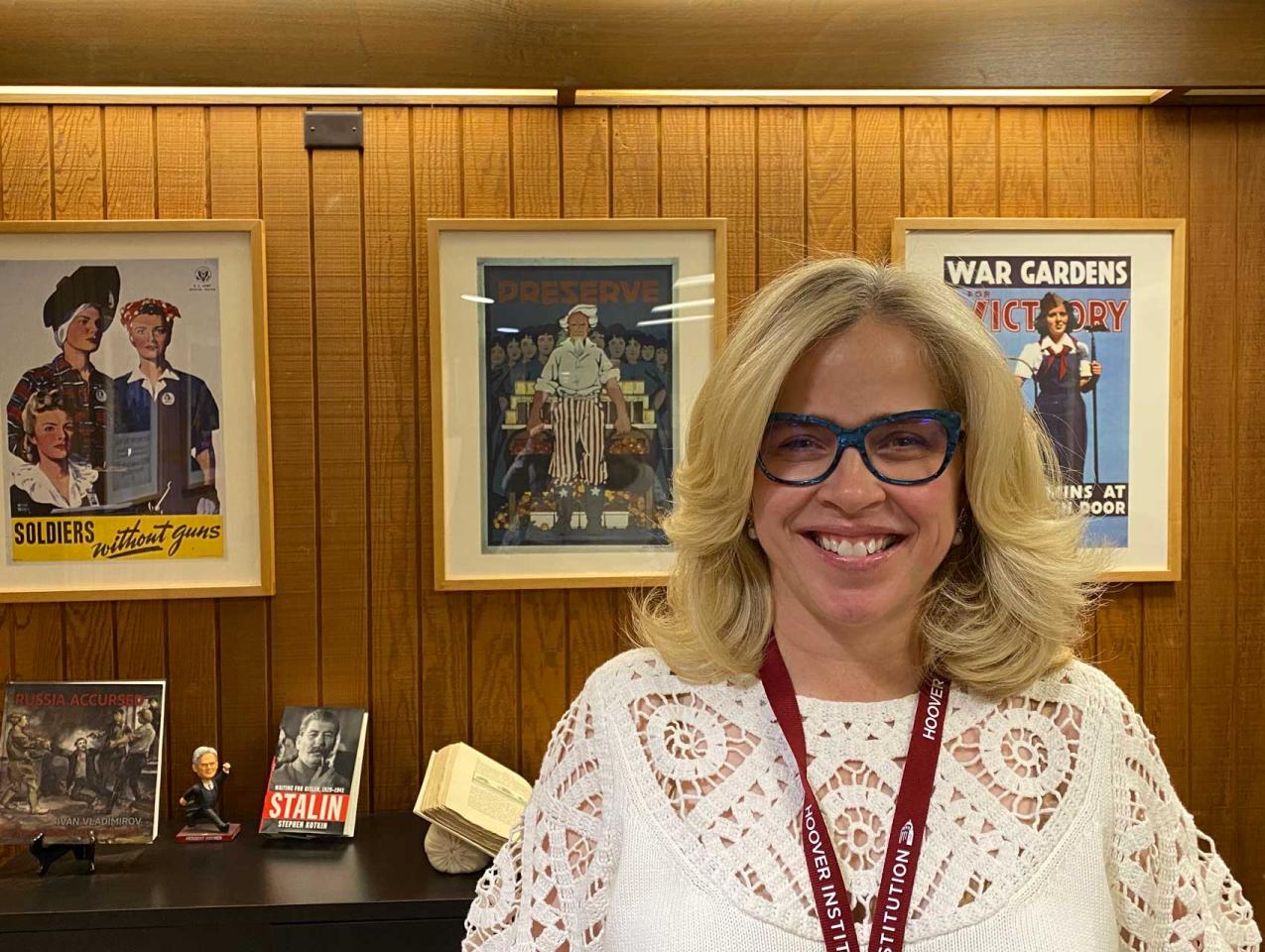 Roxanne Peck standing in front of a wall of posters and books on a table