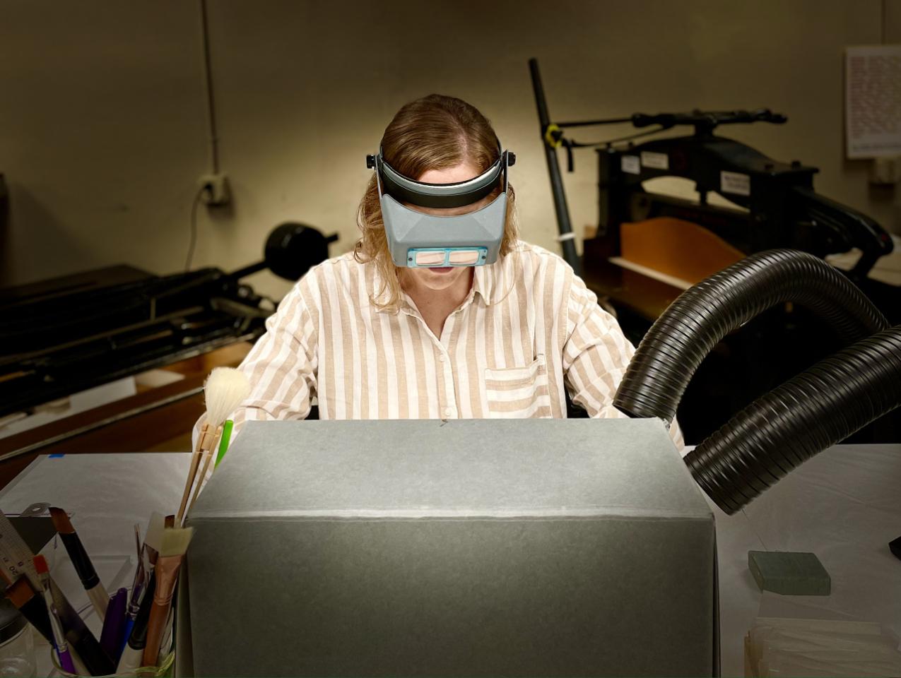 Photograph of person doing conservation work partially hidden by an archival box