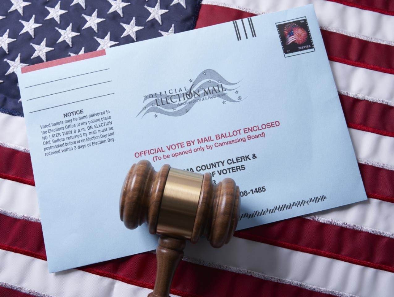 Voting ballot: Absentee voting by mail with ballot envelope on USA flag and gavel stock photo