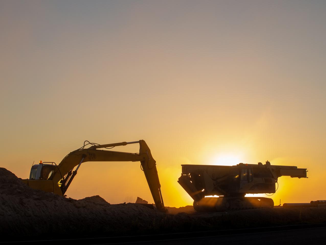 Construction machinery in the rays of the rising sun, early morning at the construction site stock photo