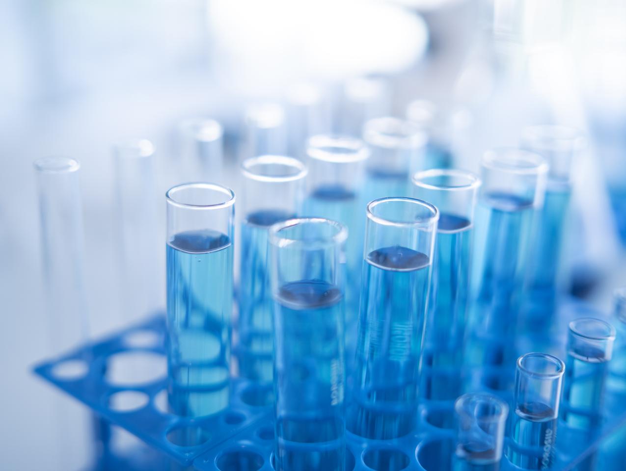 Science laboratory test tubes row with light blue liquid close-up - stock photo