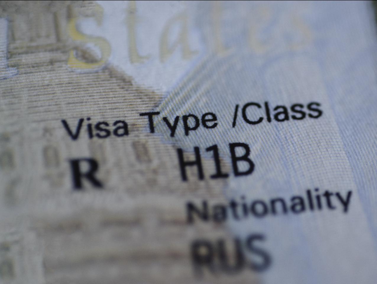 Fragment of H1B visa (for specialty workers) stamp in passport, blurred april calendar on background. H1B visa program deadline concept. Close up view. stock photo