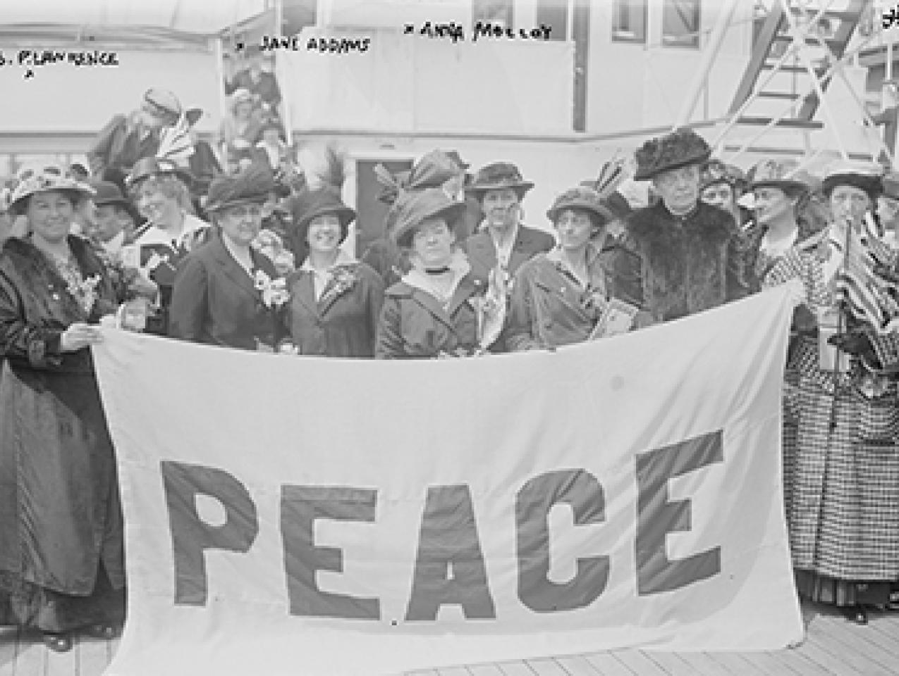 Black and white photograph of American delegates to the International Congress of Women holding a flag that reads PEACE, 1915