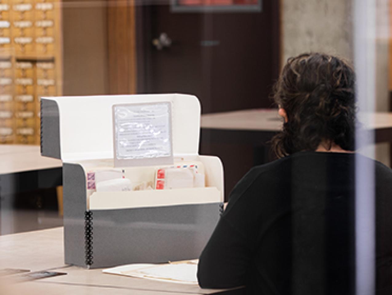 color photo of a person seated in the reading room looking at archival materials