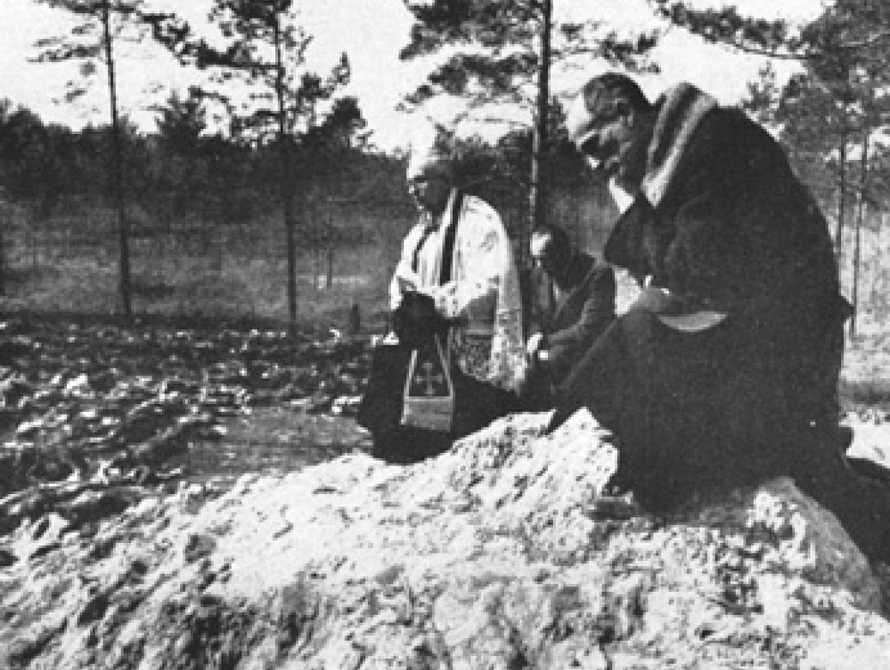 Father Stanislaw Jasinski, representative of the bishop of Krakow, prays over the mass graves