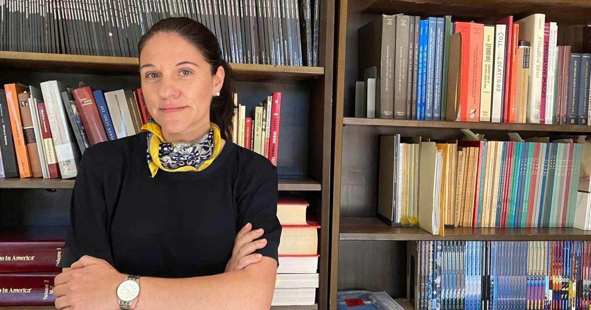 Katharina Friedla standing in front of book case