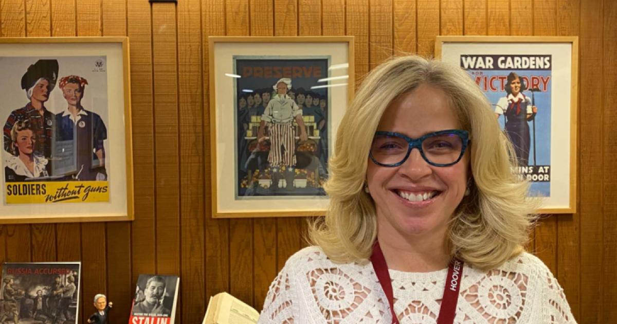 Roxanne Peck standing in front of a wall of posters and books on a table