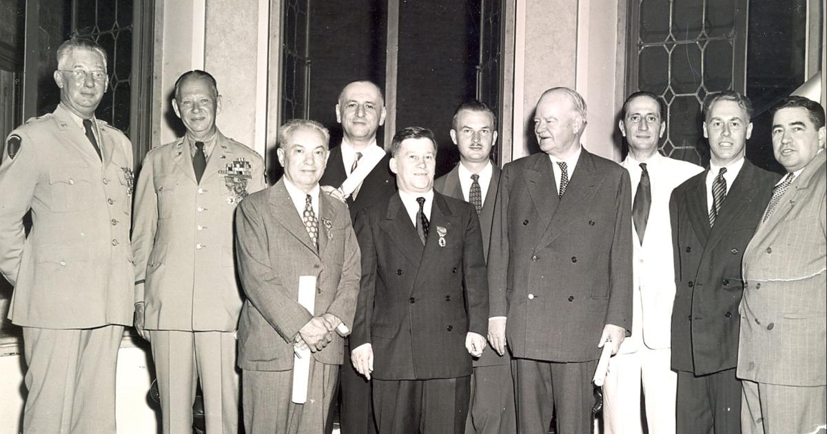 Group of men standing for a photo. Nicholas Feodoroff (front row center) with Herbert Hoover (front row right).