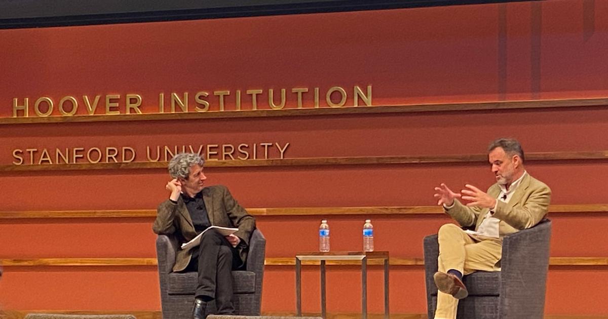 Alex de Waal and Niall Ferguson sitting on the stage of Hauck Auditorium