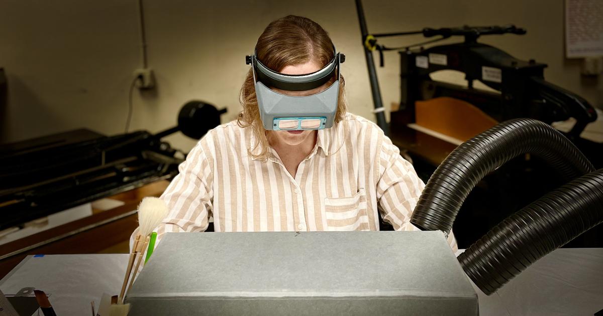 Photograph of person doing conservation work partially hidden by an archival box