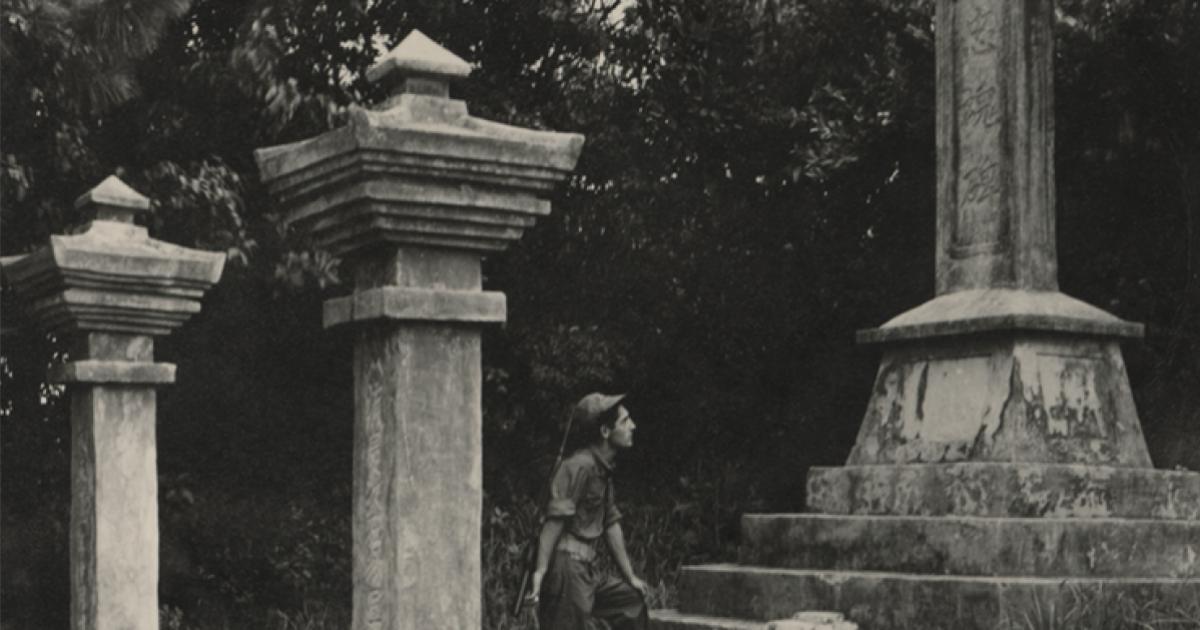 Black and white photograph of a US Navy Seabee exploring a monument on Okinawa durring WWII