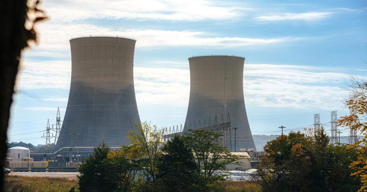 Green Trees surrounding the tall Cooling Towers of a Nuclear Power Plant in Tennessee on a Sunny Autumn Day stock photo