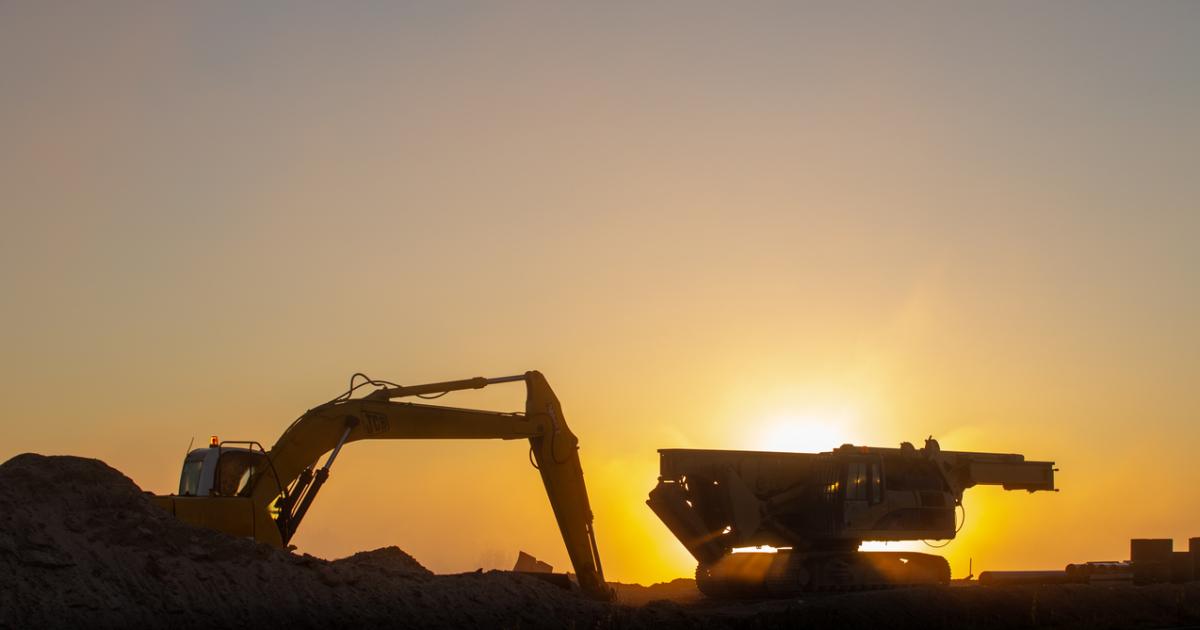 Construction machinery in the rays of the rising sun, early morning at the construction site stock photo