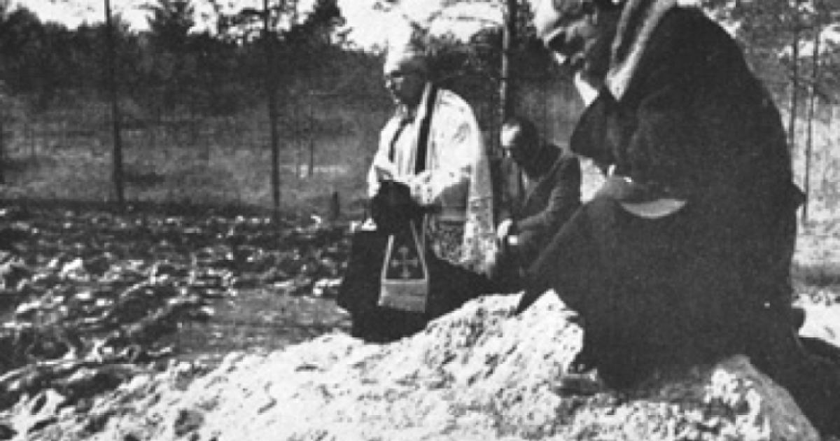 Father Stanislaw Jasinski, representative of the bishop of Krakow, prays over the mass graves