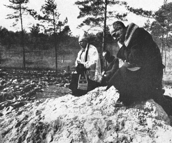 Father Stanislaw Jasinski, representative of the bishop of Krakow, prays over the mass graves