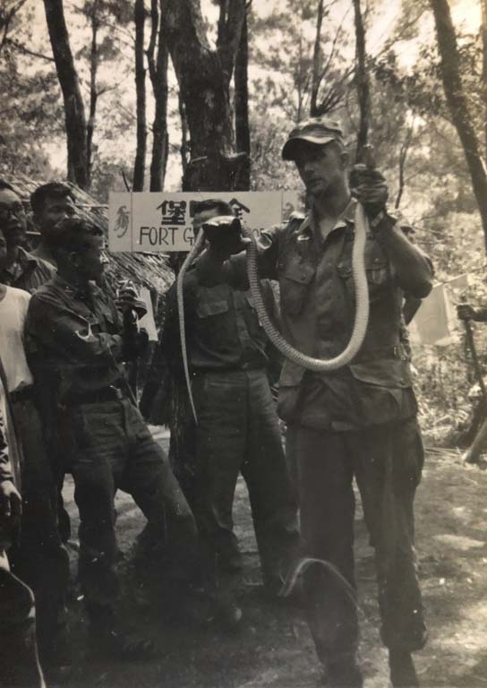 black and white photo of a military training with man holding a snake standing with a group of men