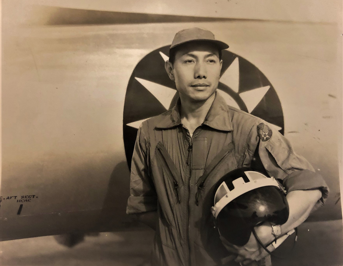 Zhou Shilin in the 1950s posing for a photograph in front of a plane carrying a helmet
